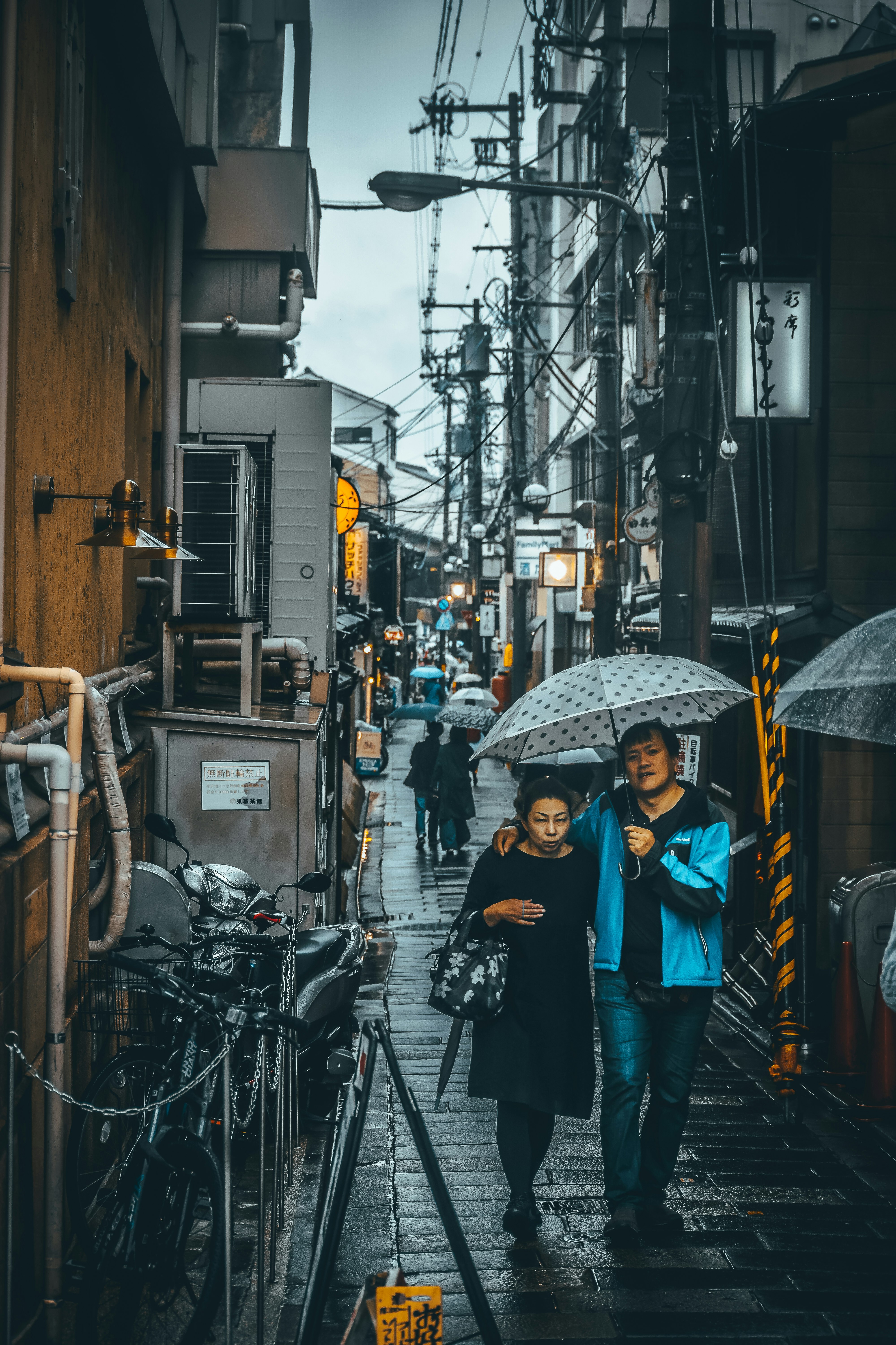 woman in black jacket holding umbrella while walking on sidewalk during daytime